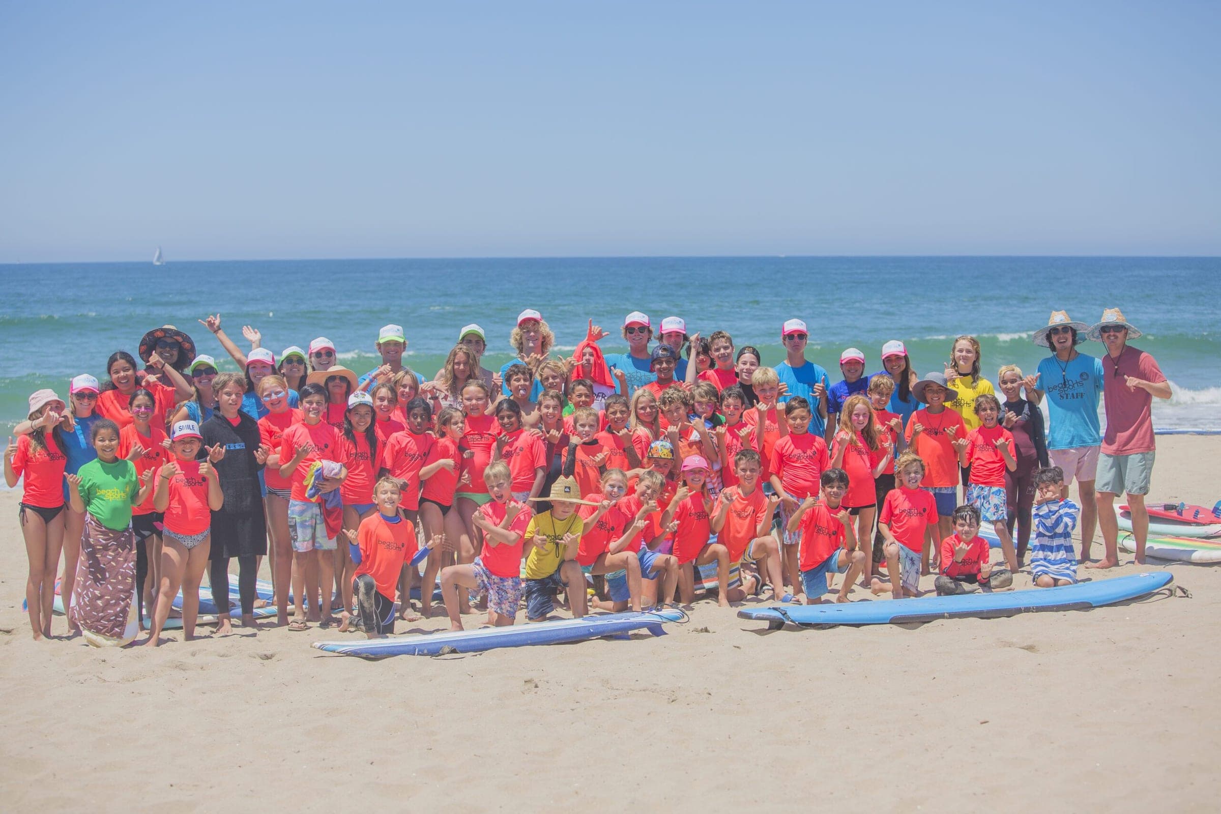 A large group of BeachSports campers in the water with coaches, at the beach