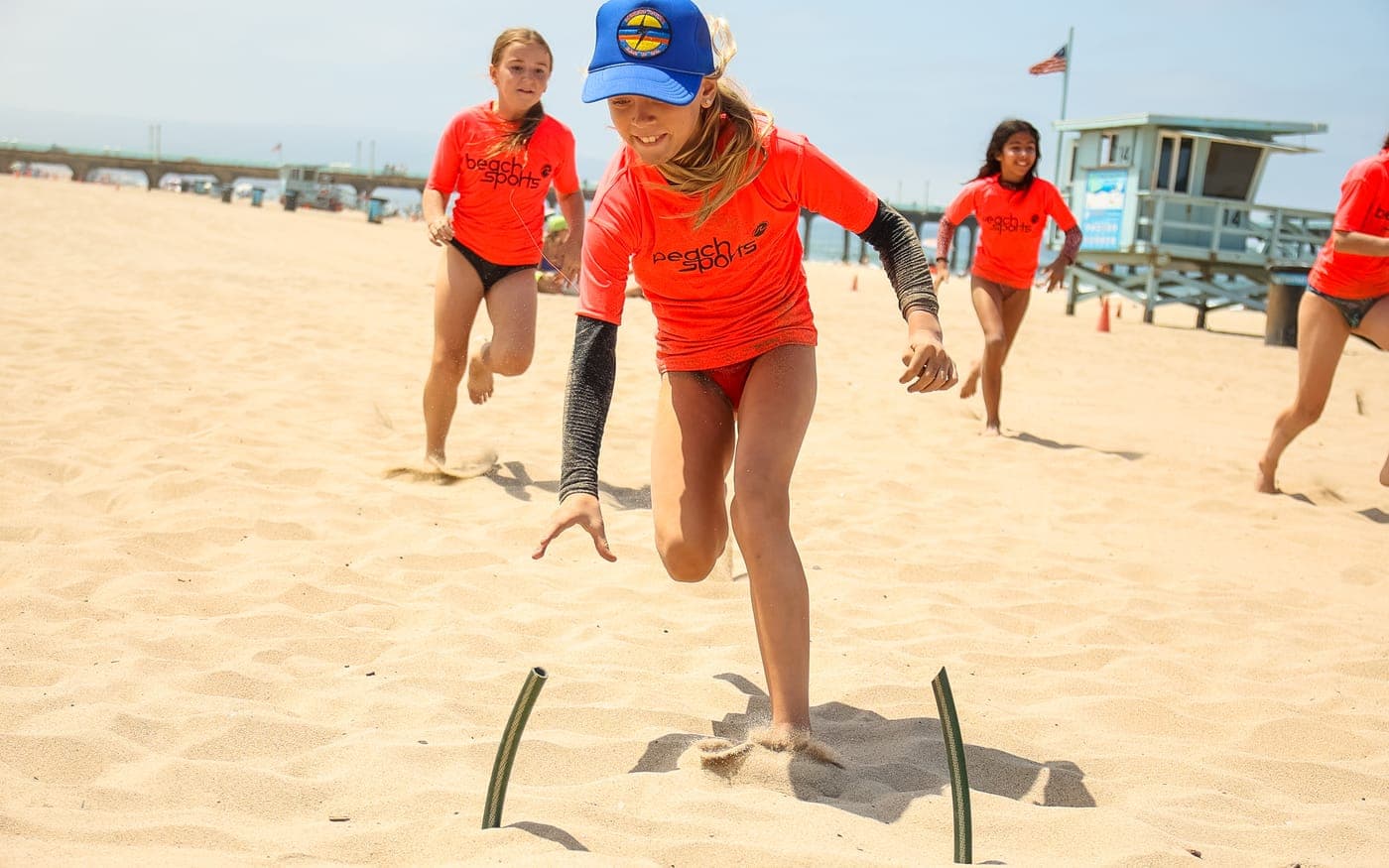 BeachSports campers sprinting for a flag in a Junior Lifeguard flags race on the sand at Manhattan Beach.