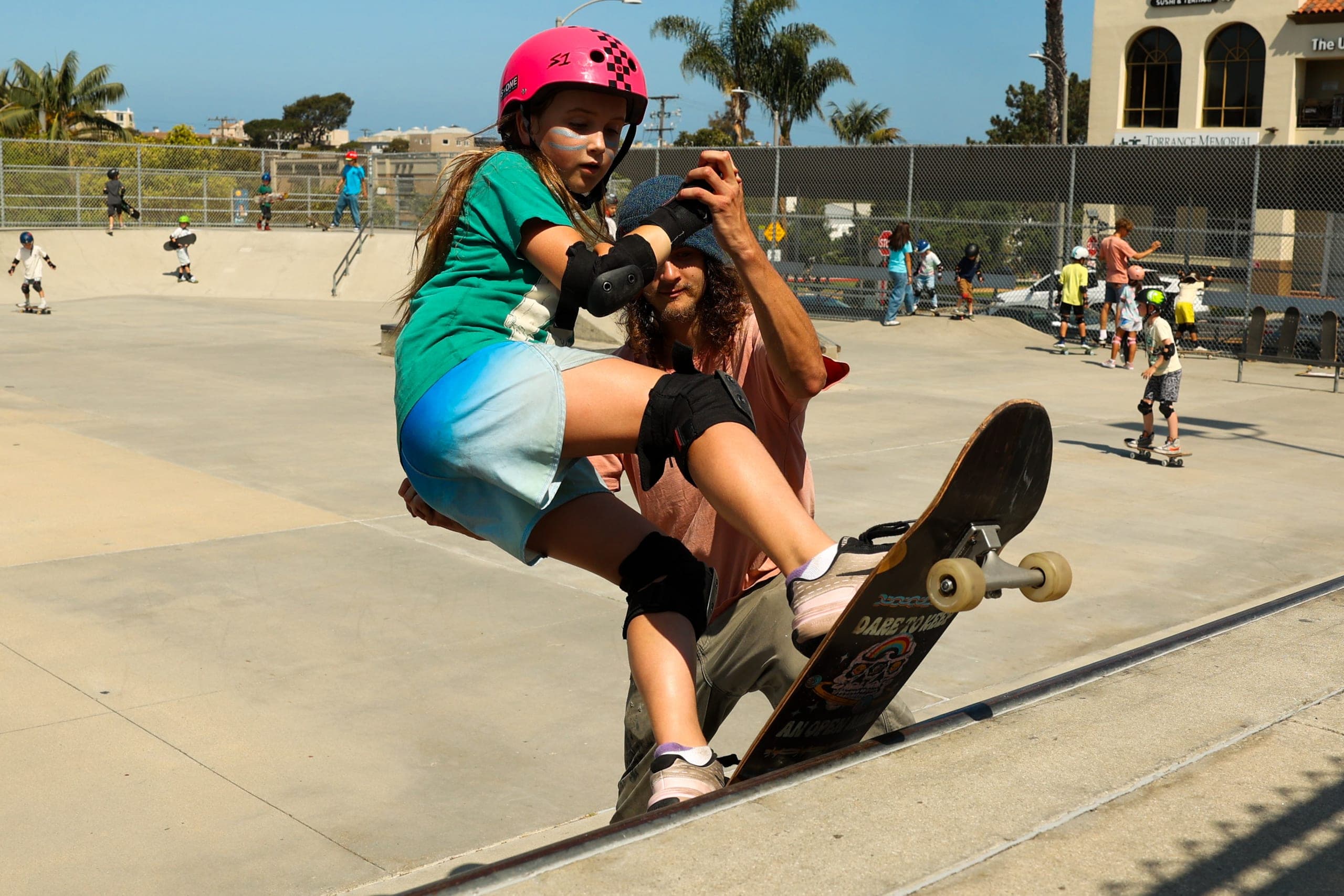 A BeachSports skate coach guiding young riders on the ramps at the Hermosa Beach Skatepark.