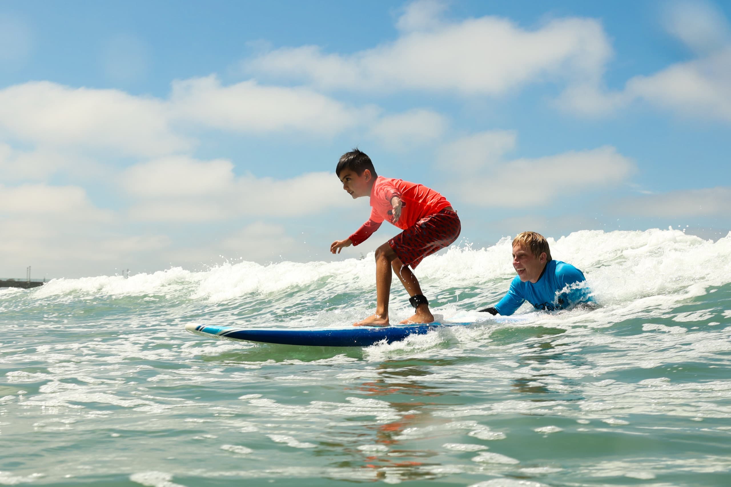 A BeachSports coach cheering on a camper riding a wave at Manhattan Beach.