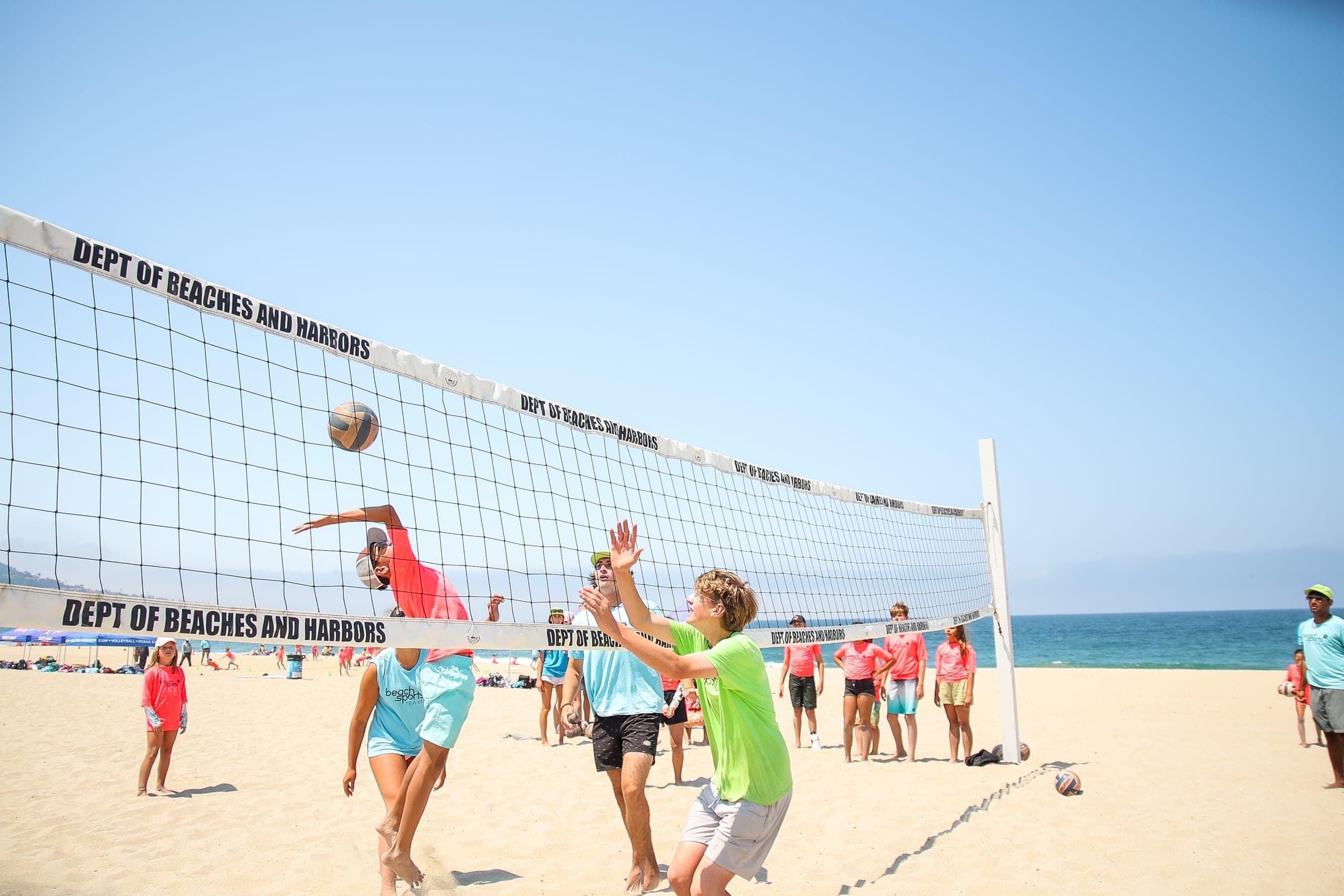 A camper spiking the ball at the net during a match