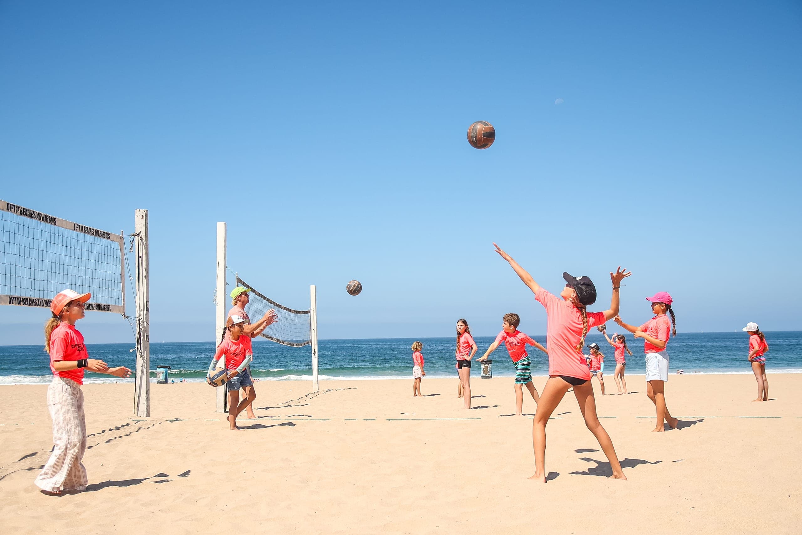 A camper serving during a beach volleyball match