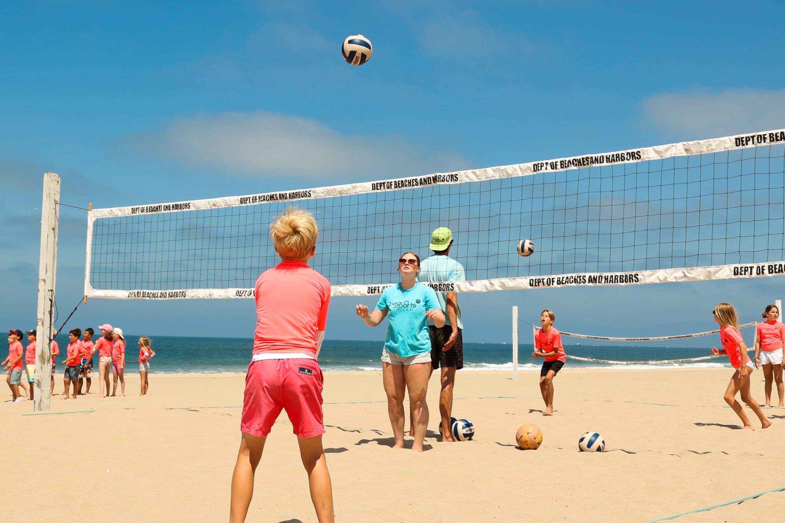 Multiple courts of campers playing volleyball on the sand