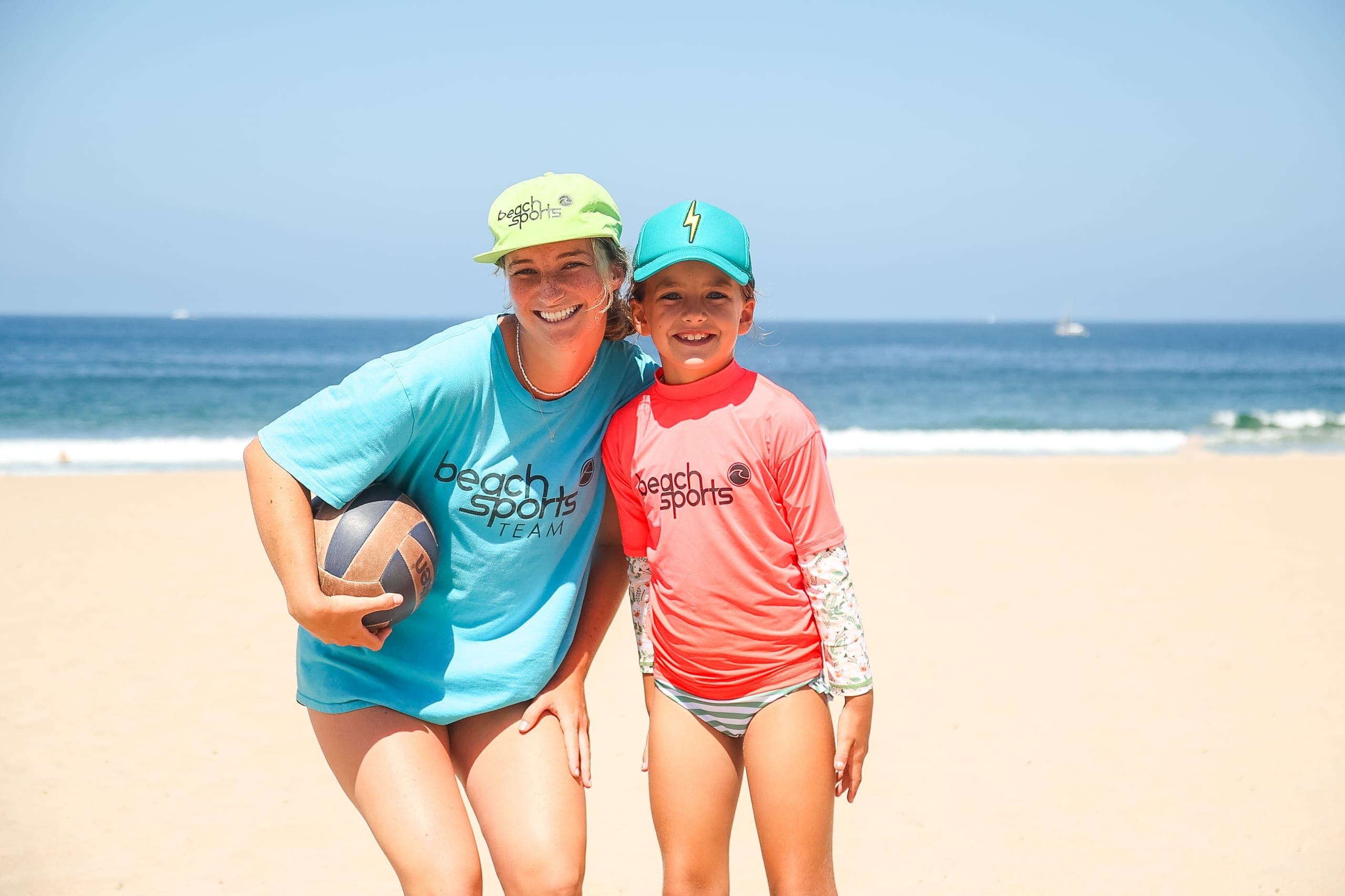 A coach and camper smiling together on the sand