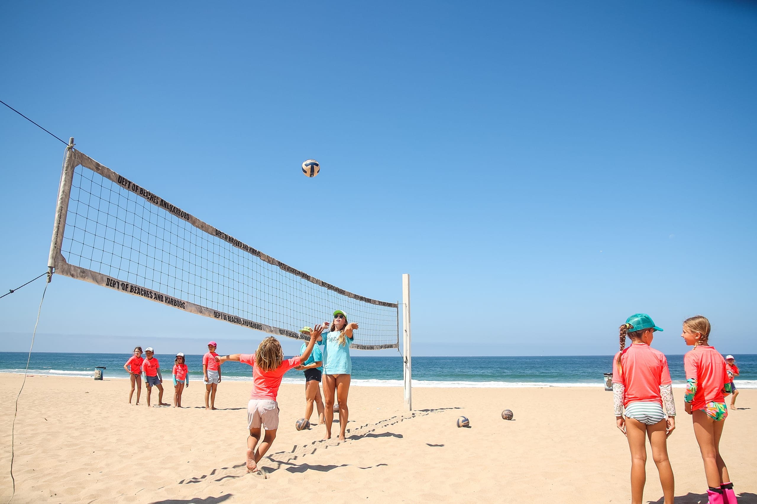 Campers gathered at the net during a beach volleyball match