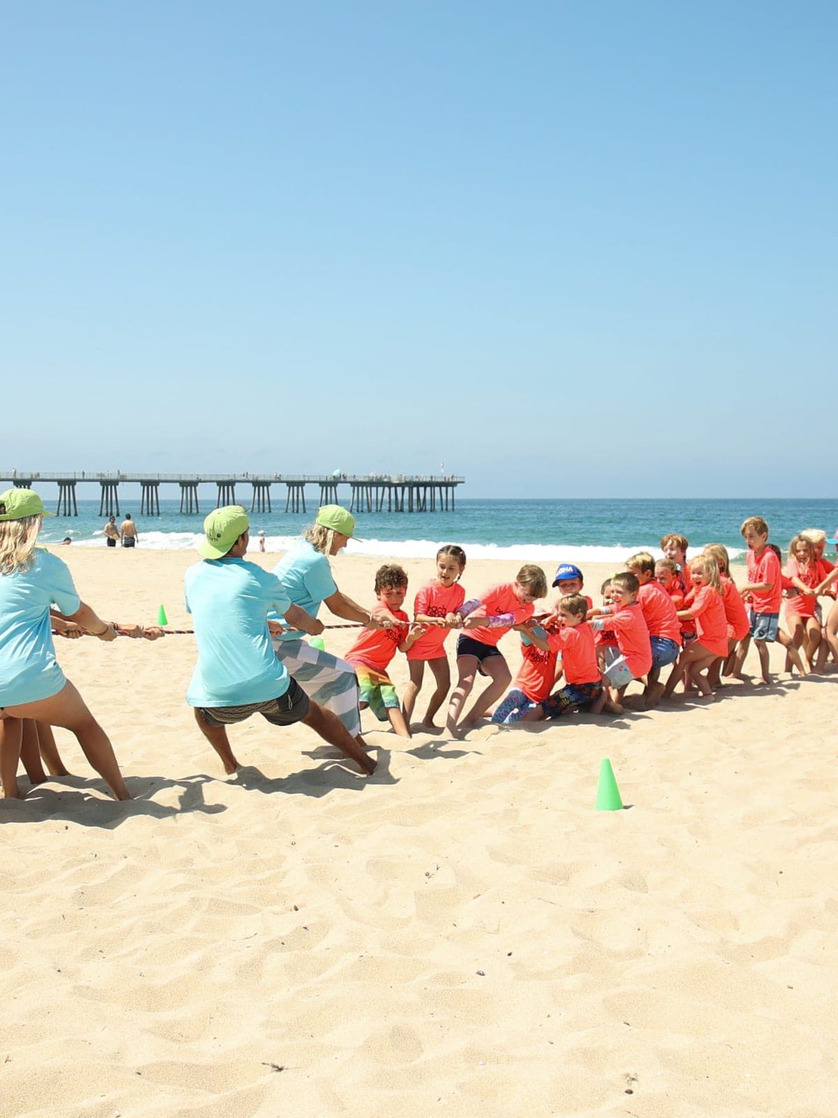 BeachSports coaches and campers playing tug-of-war together on the sand