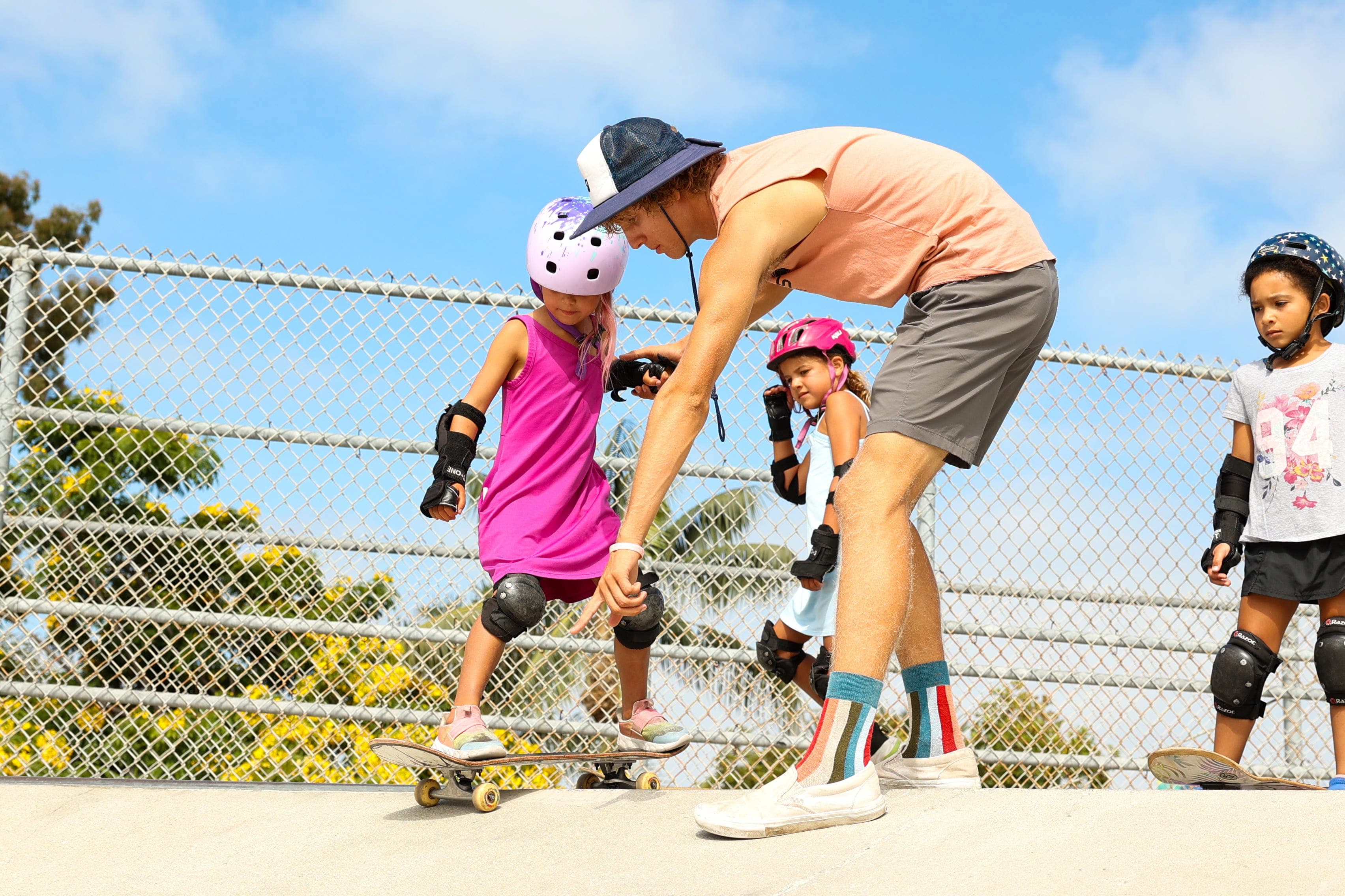 A BeachSports coach guiding a young skater at the Hermosa Beach Skatepark