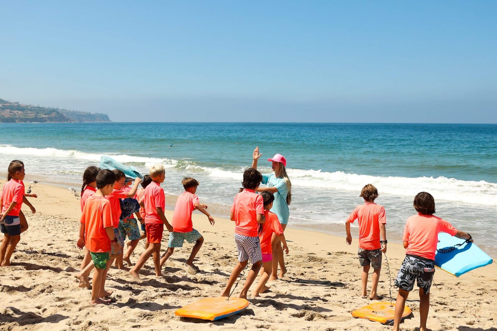 A BeachSports coach with a group of campers and boogie boards at a beach party